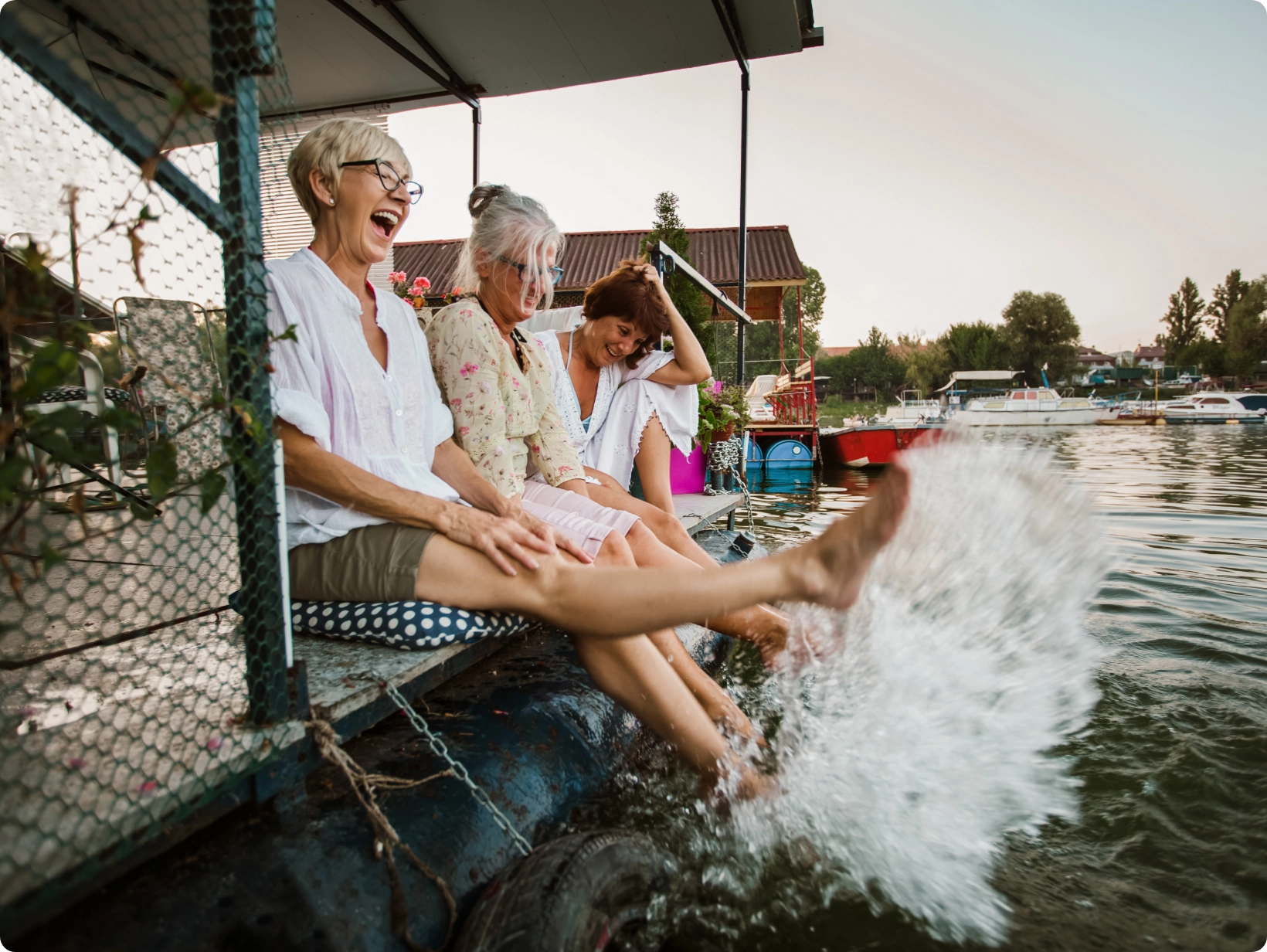 women’s-health-antiox-protection Three adult women sitting on a boat within a harbor with their legs hanging off the boat side kicking the water playfully.