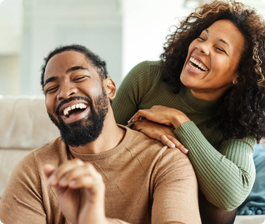 womens-health-related-posts-3 Male and female couple sitting and laughing together in a living room.