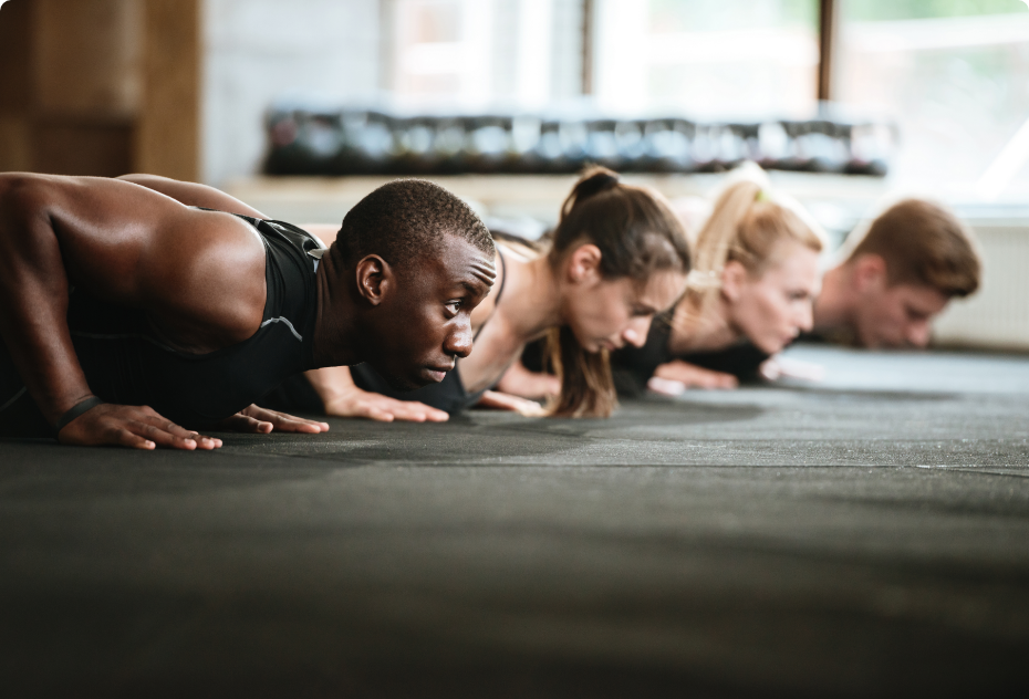 Athletes performing push-up exercises on a gym floor during a group training session.